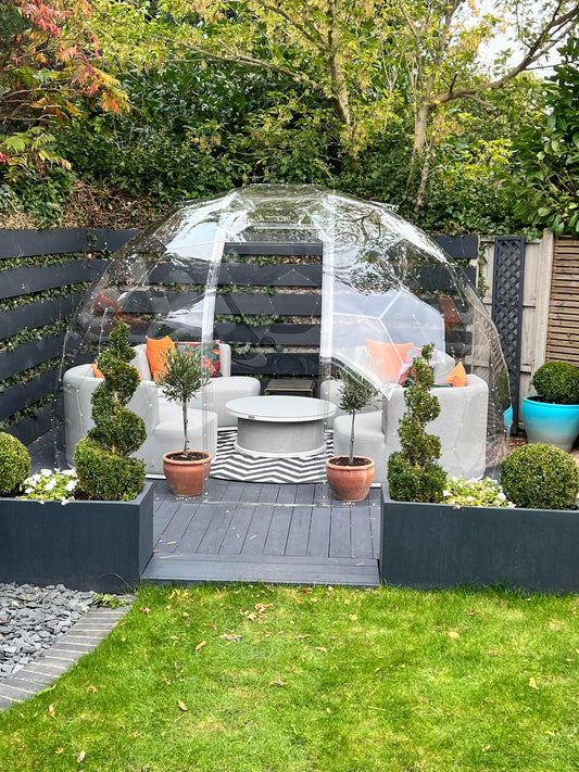 A GeoDomeX dome with white chairs and topiary in a modern garden