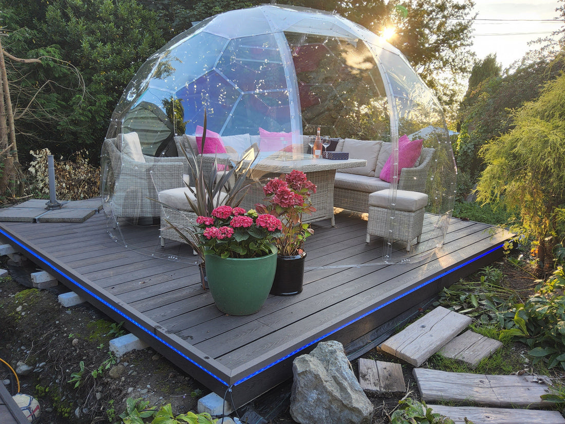 A GeoDomeX dome on grey composite decking with flowers and garden furniture